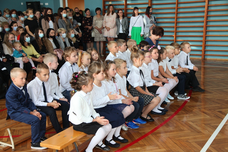 Uczniowie podczas rozpoczęcia roku szkolnego siedzący na sali gimnastycznej
