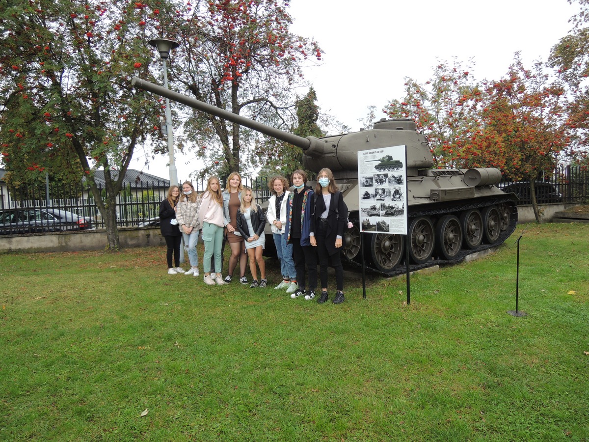 - Zdjęcie przedstawia uczniów klasy ósmej pozujących przy czołgu.