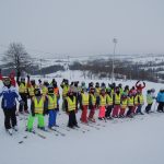 pamiątkowe zdjęcie uczestników zimowiska z opiekunami i instruktorami na stoku stacji narciarskiej CzerwienneSki.