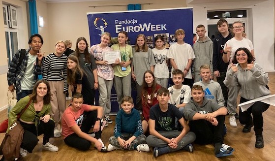 Grupa uczniów z wolontariuszami na tle planszy Euroweek