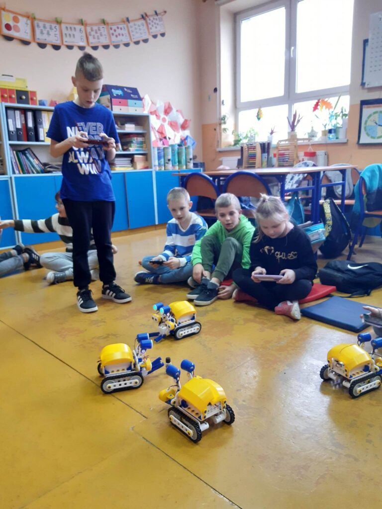 Grupa uczniów podejmuje próbę kierowania robotami