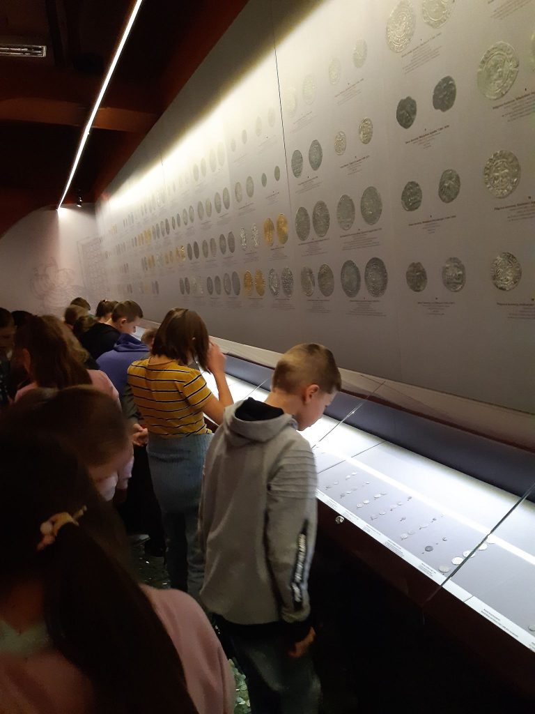 Uczniowie oglądają wystawę monet.