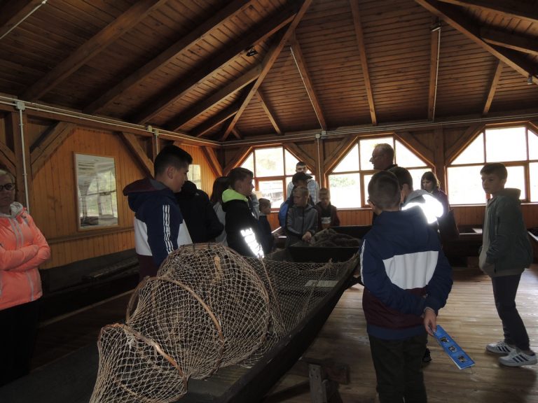 Uczestnicy wycieczki dowiadują się o sposobach połowu ryb na rzece Pilicy.