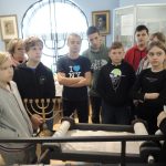 Uczniowie słuchają informacji o kulturze społeczności żydowskiej mieszkającej w Ciechanowie oglądając kopię Tory