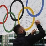 Konrad Niedźwiedzki składa podpis na fladze olimpijskiej.