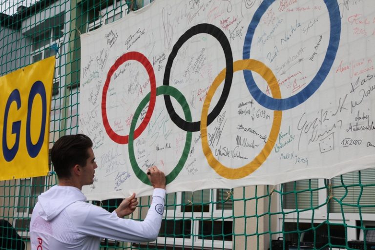 Kajetan Duszyński składa podpis na fladze olimpijskiej.