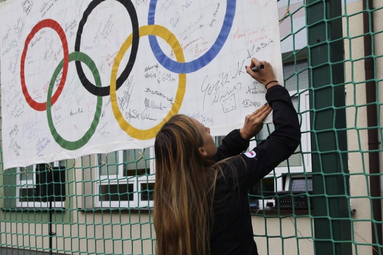 Katarzyna Woźniak-Niedźwiedzka składa podpis na fladze olimpijskiej.