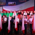 Na scenie uczniowie z klas I – III i ósmoklasiści z flagami Polski
