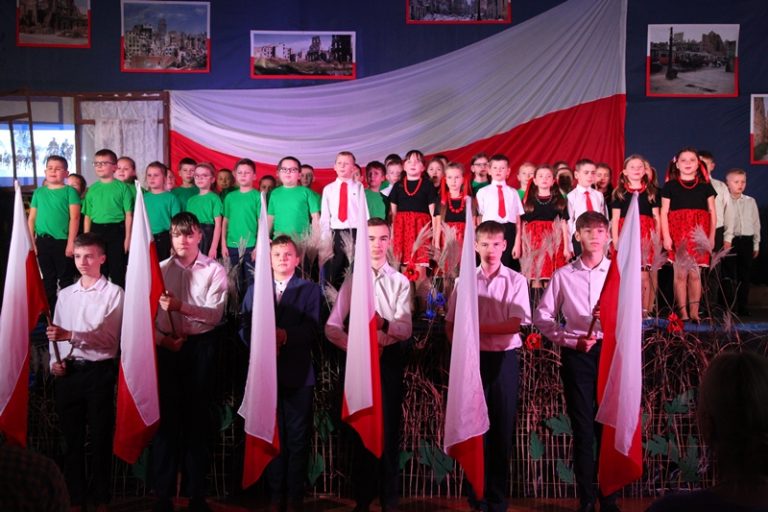 Na scenie uczniowie z klas I – III i ósmoklasiści z flagami Polski