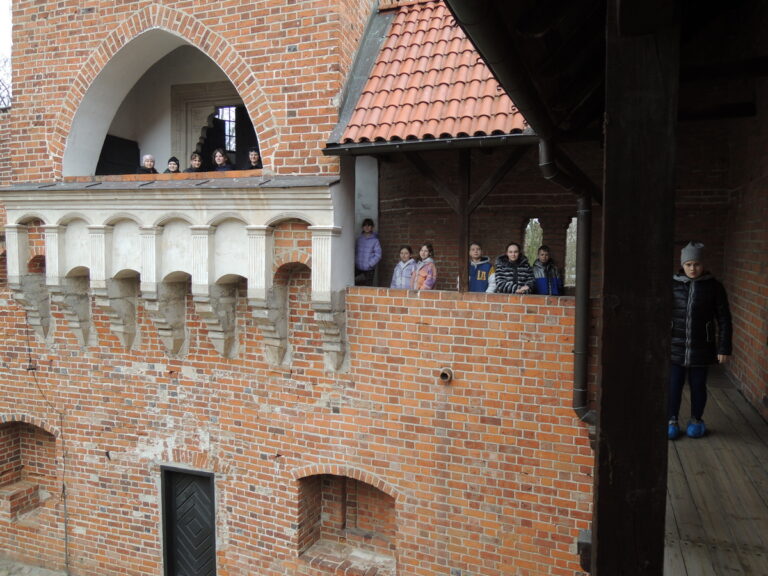 Uczestnicy wycieczki spacerują po krużgankach oporowskiego zamku.