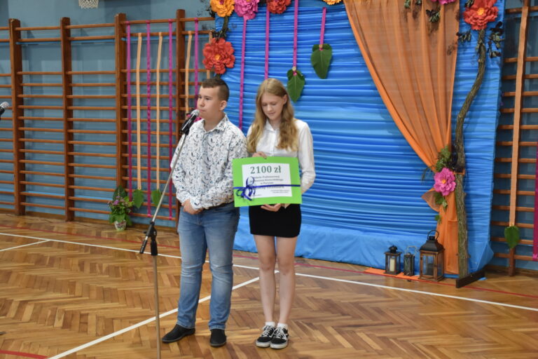 Uczniowie klas ósmych Kornelia Serwach i Jakub Petera przekazują prezent  na zakup nowego Sztandaru. 
