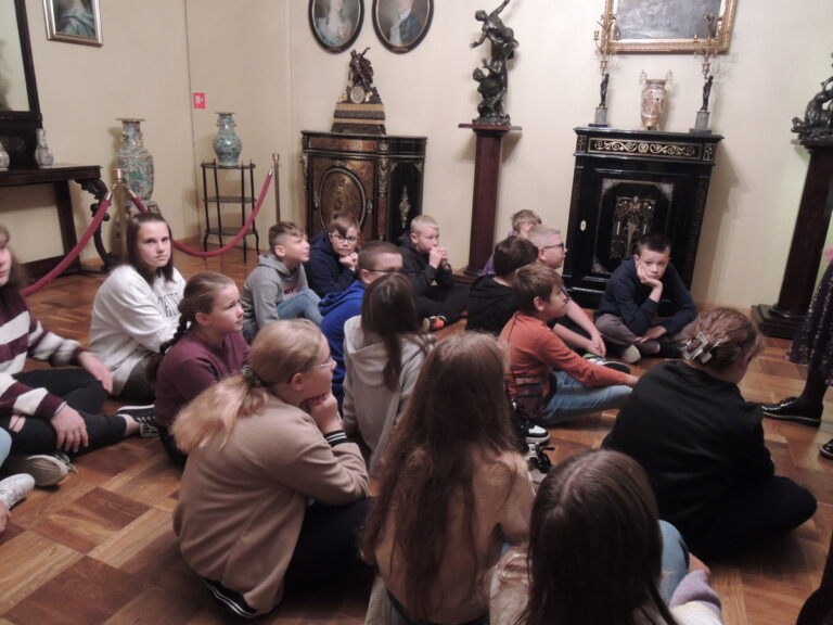 Uczniowie słuchają informacji o ekspozycji muzealnej X wieków Płocka.
