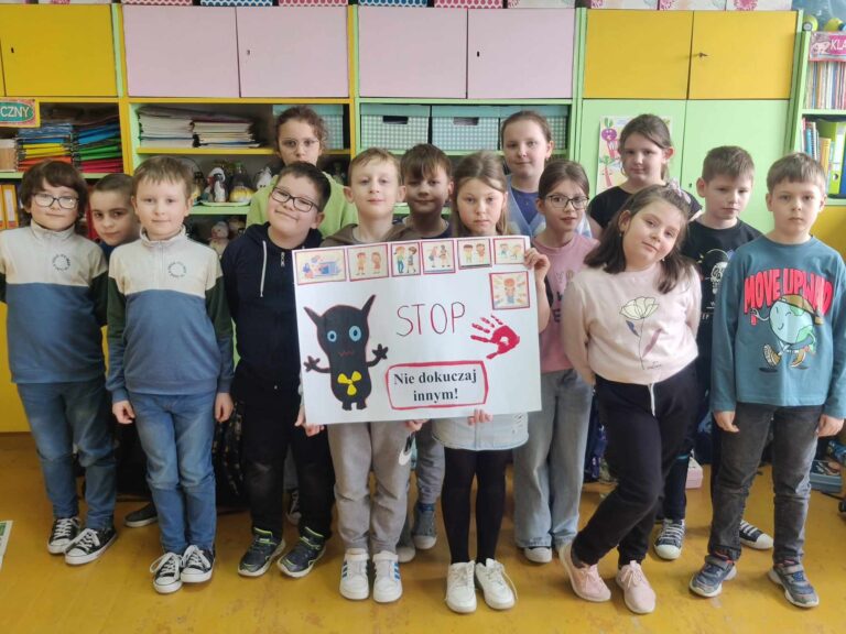 Uczniowie klasy II a, prezentujący plakat „Stop - Nie dokuczaj innym”.