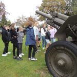 Zdjęcie przedstawia uczniów klasy ósmej oglądających eksponaty zgromadzone na dziedzińcu Muzeum Bitwy Nad Bzurą.