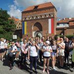 Grupa uczestników wycieczki do Torunia wraz z przewodnikiem przy wejściu na Stare Miasto.