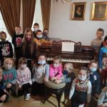 Grupa uczniów przy fortepianie na którym grał Fryderyk Chopin.