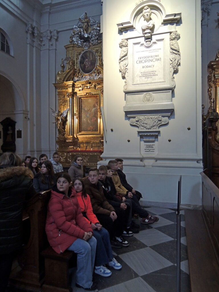 Uczestnicy wycieczki słuchają opowieści o sercu kompozytora Fryderyka Chopina w kościele Św Krzyża.