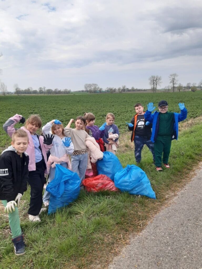 Uczniowie klasy II zbierający śmieci na swoim terenie.