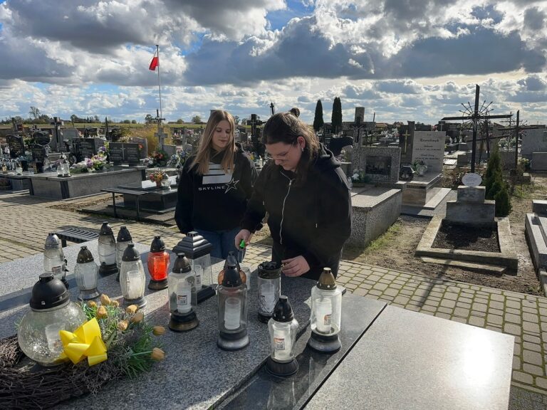 Delegacja uczniów zapala znicze na grobach zmarłych pracowników szkoły