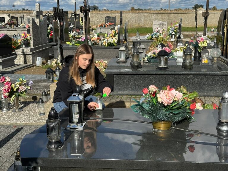 Delegacja uczniów zapala znicze na grobach zmarłych pracowników szkoły