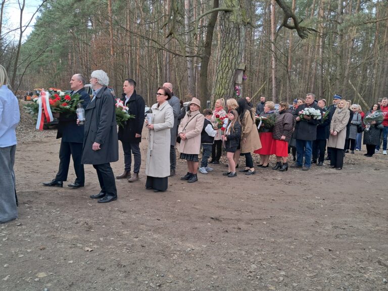 Przedstawiciele samorządów, instytucji, szkół i organizacji w przemarszu z kwiatami.